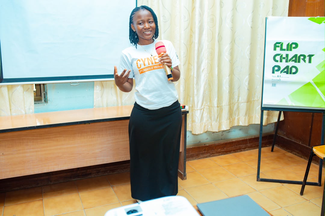 Keynote speaker holding a microphone on stage delivering a presentation.