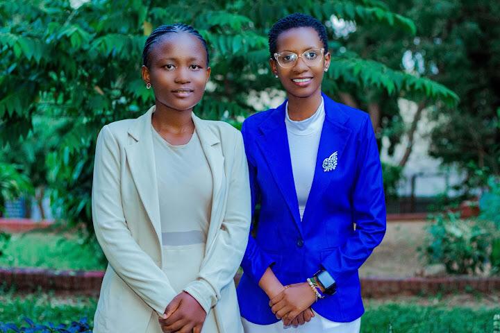 Two professional leaders standing side-by-side, smiling confidently in a well-lit corporate setting.