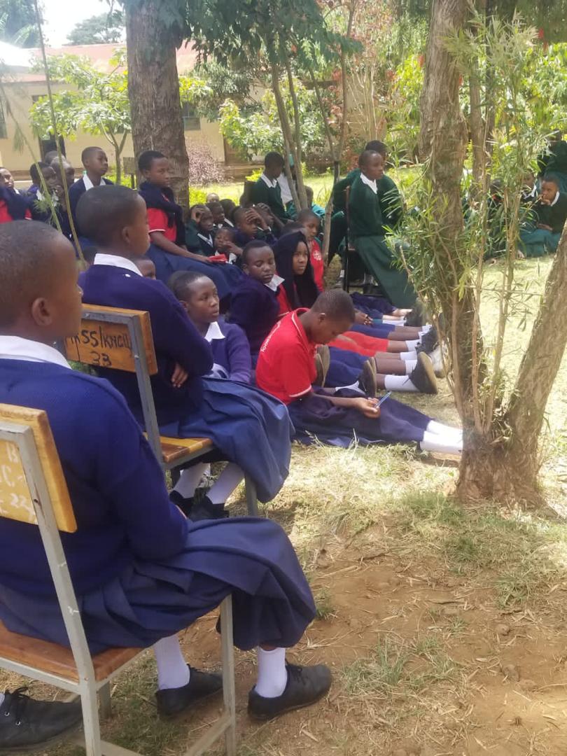 A mentor speaking passionately to a classroom of engaged secondary school students during a leadership workshop at Mkombole Secondary School in Moshi Vijijini.