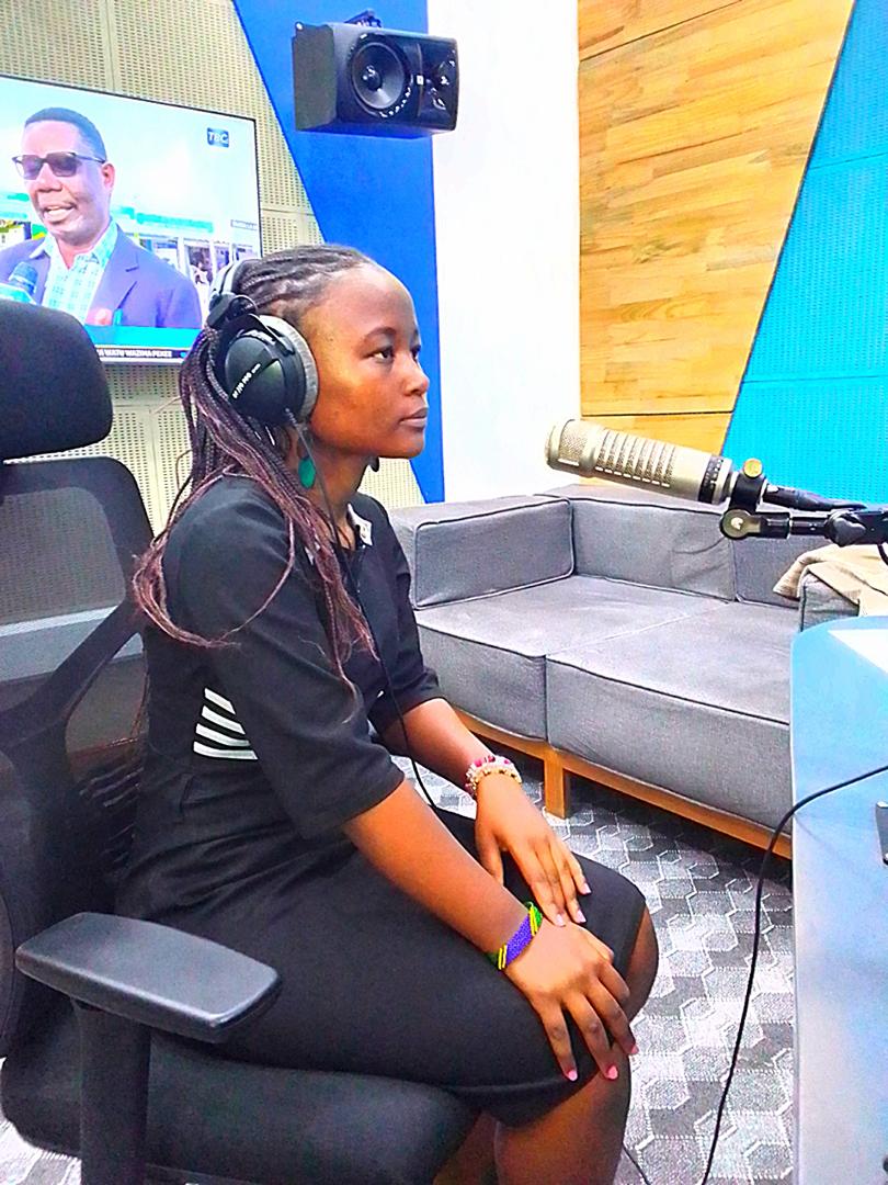 An environmental advocate speaking into a professional microphone during a live studio interview at TBC Radio to mark World Environment Day 2025.