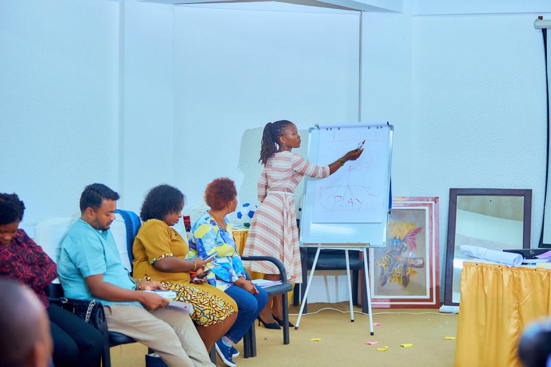 A presenter leading a visual slide session about early childhood learning frameworks during an Arigatou International training workshop.