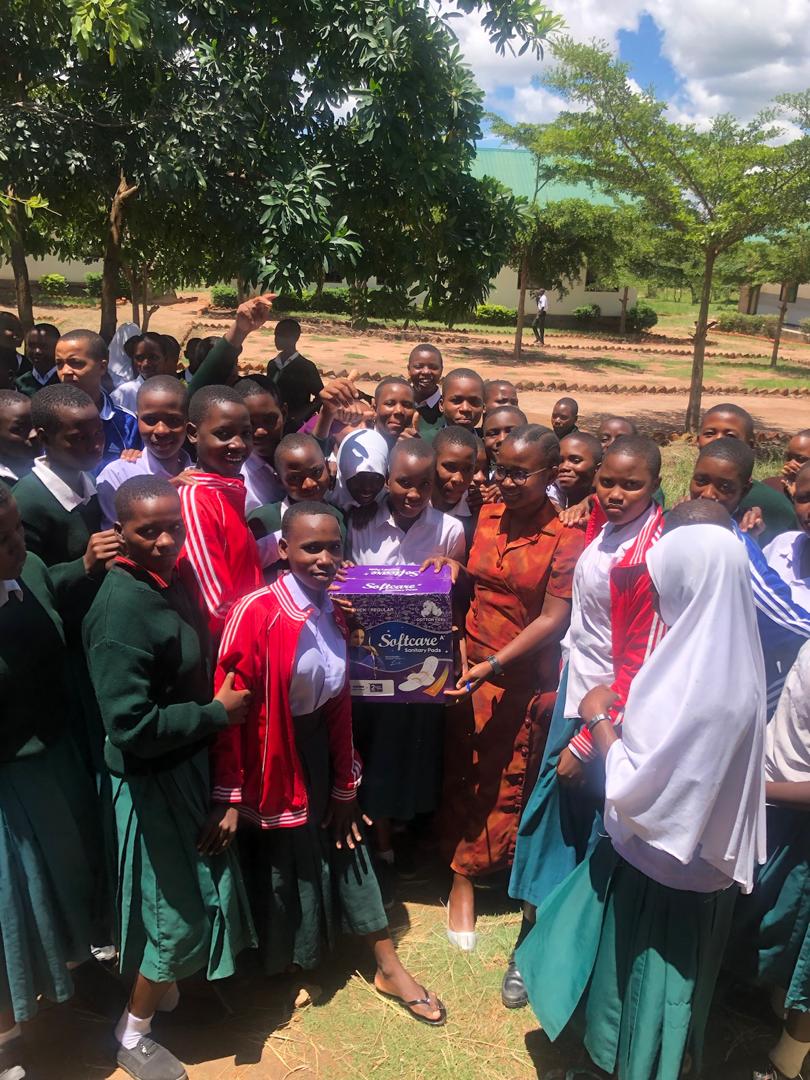 An advocate collaborating with ward leaders to distribute menstrual pad packages to schoolgirls during an International Women's Day event.